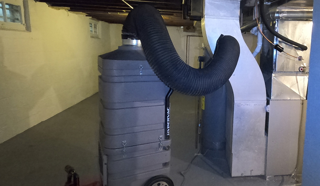 HEPA rated duct cleaning vacuum plugged into a furnace plenum.