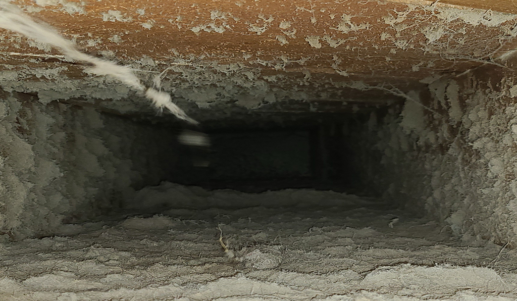 Inside of a return duct that is covered in dust and debris.